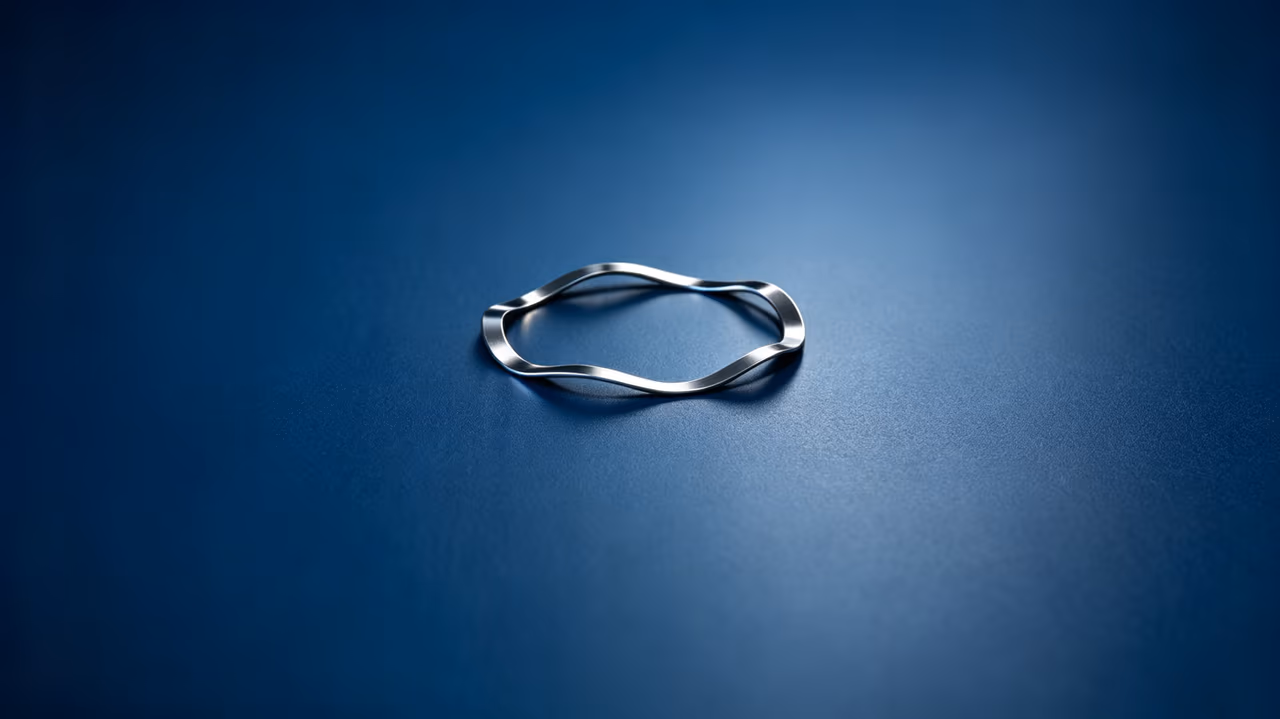 Single-turn flat wire wave spring on a blue industrial background
